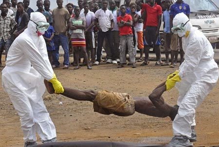 Các chuyên gia y tế đang di dời thi thể một người đàn ông chết vì nhiễm virus Ebola trước sự chứng kiến của đám đông tại thủ đô Monrovia của Liberia. Ảnh: AP