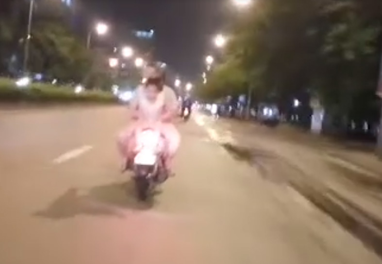 Người phụ nữ chở 2 đứa trẻ ngồi ngược, chạy băng băng trên đường