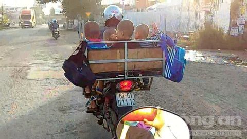 Người phụ nữ chở 4 trẻ em trong lồng sắt, chạy bon bon trên đường