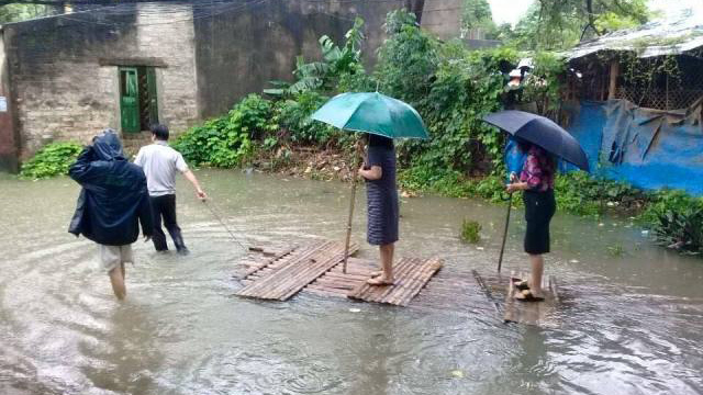 Nữ chủ tịch phường cầm ô đứng trên bè, được kéo đi thị sát lụt