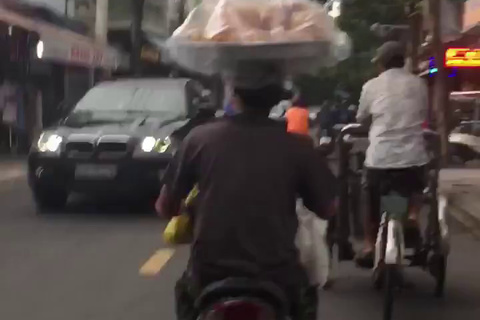 Đội mâm bánh mỳ trên đầu và màn 'uốn éo' của người đàn ông trên xe máy