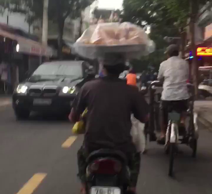 Đội mâm bánh mỳ trên đầu và màn 'uốn éo' của người đàn ông trên xe máy